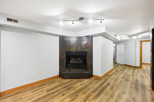 unfurnished living room with a tile fireplace and light hardwood / wood-style flooring