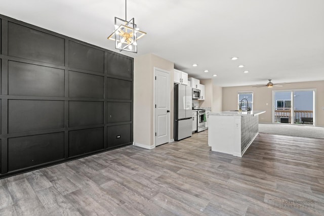 kitchen with stainless steel appliances, sink, pendant lighting, light hardwood / wood-style flooring, and white cabinetry