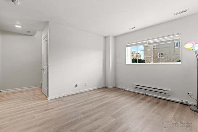 empty room featuring a baseboard radiator and light hardwood / wood-style floors