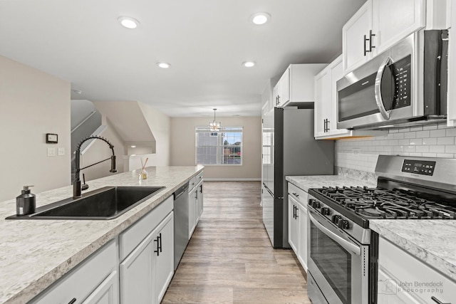 kitchen featuring appliances with stainless steel finishes, tasteful backsplash, sink, light hardwood / wood-style flooring, and white cabinetry