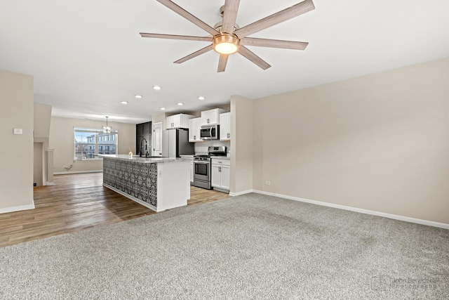 kitchen featuring a kitchen island with sink, white cabinets, sink, light hardwood / wood-style floors, and stainless steel appliances