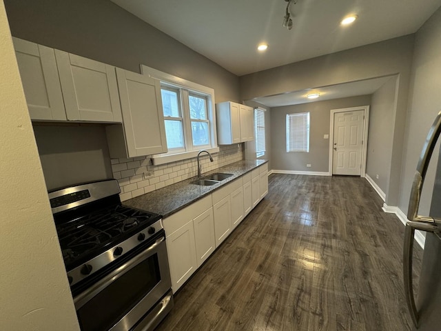 kitchen featuring stainless steel gas stove, sink, dark wood-type flooring, decorative backsplash, and white cabinets