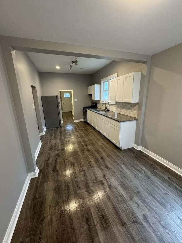 kitchen with backsplash, black range oven, white cabinets, sink, and dark hardwood / wood-style floors