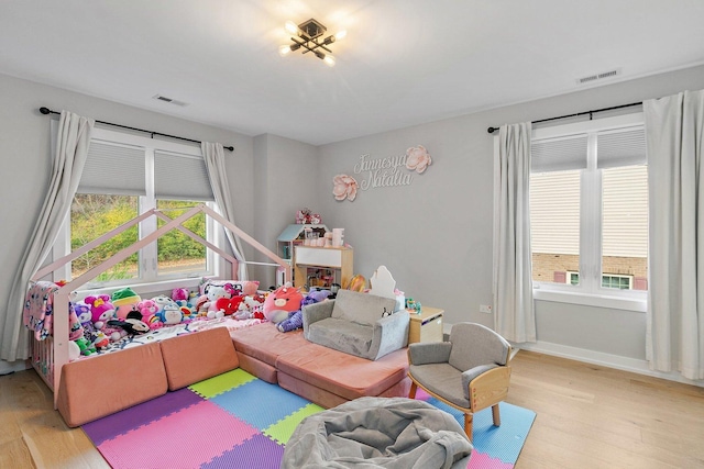 game room with a wealth of natural light and light hardwood / wood-style flooring