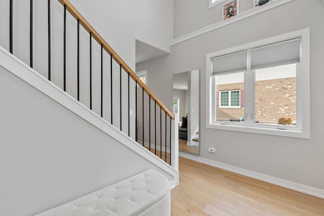 stairs with hardwood / wood-style floors and a towering ceiling