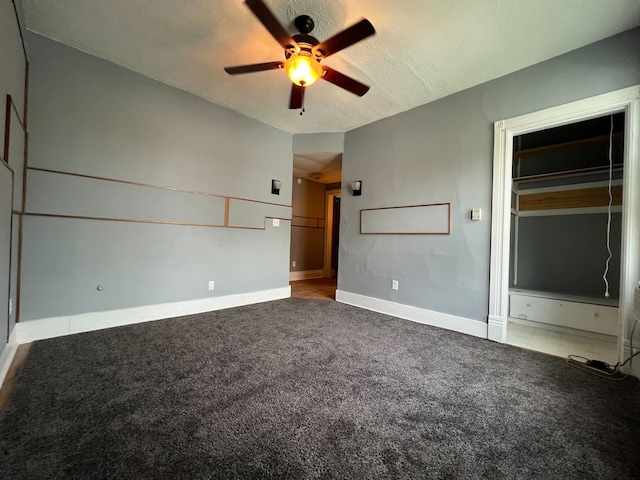 empty room featuring a textured ceiling, dark carpet, and ceiling fan