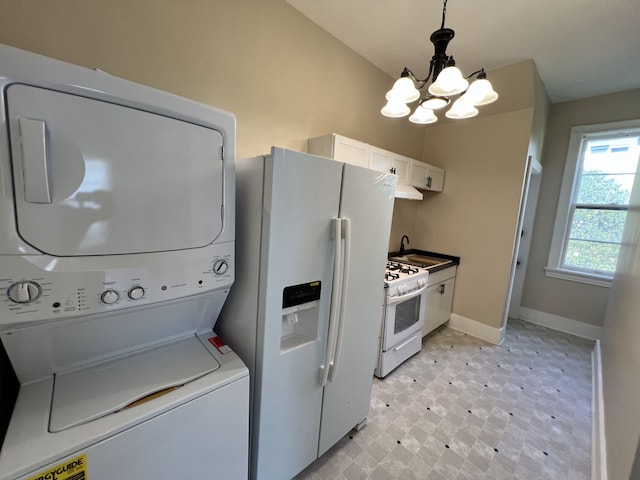 laundry area featuring stacked washer / dryer, sink, and a chandelier