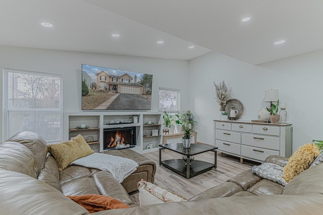 living room featuring a wealth of natural light, light hardwood / wood-style floors, and vaulted ceiling