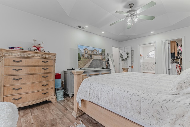 bedroom featuring connected bathroom, ceiling fan, light hardwood / wood-style floors, a walk in closet, and a closet