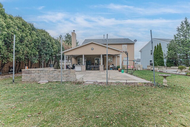 rear view of house featuring a lawn and a patio