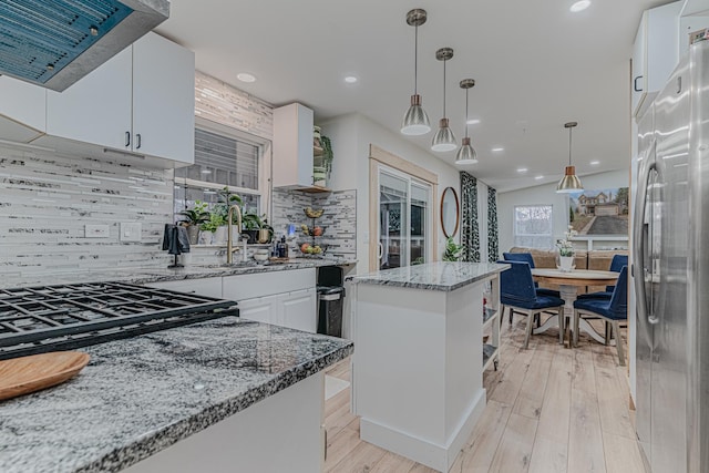 kitchen featuring exhaust hood, white cabinets, sink, decorative backsplash, and stainless steel fridge