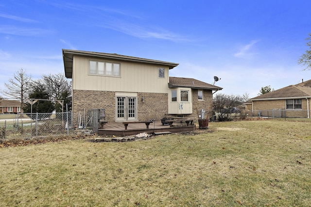 rear view of property with a wooden deck and a lawn