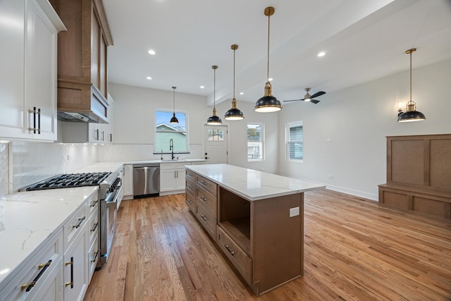 kitchen with pendant lighting, a center island, white cabinets, light hardwood / wood-style floors, and stainless steel appliances