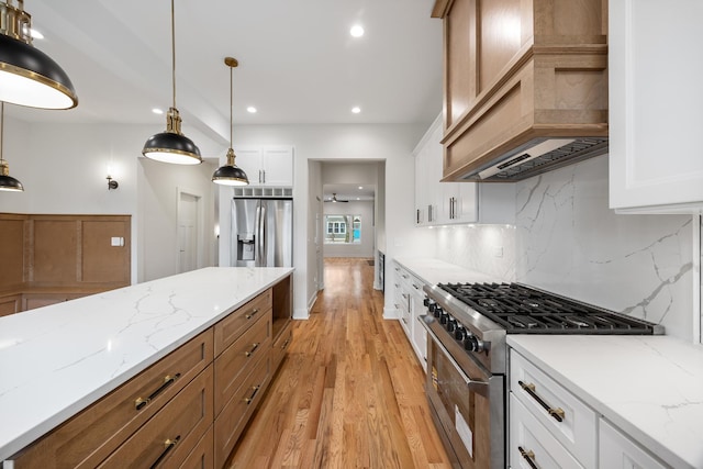 kitchen featuring white cabinetry, hanging light fixtures, light hardwood / wood-style flooring, decorative backsplash, and appliances with stainless steel finishes