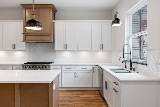 kitchen featuring decorative light fixtures, light stone counters, white cabinetry, and sink