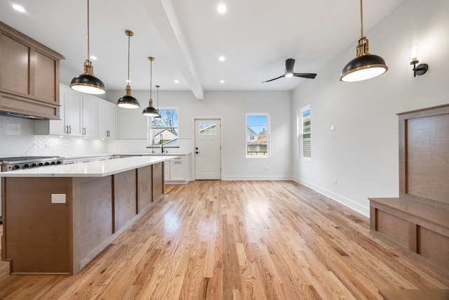 kitchen featuring a kitchen island, ceiling fan, beamed ceiling, light hardwood / wood-style floors, and white cabinetry