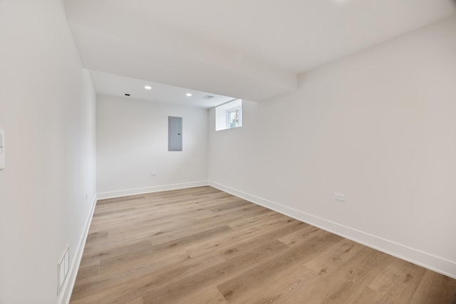 spare room with electric panel and light hardwood / wood-style flooring