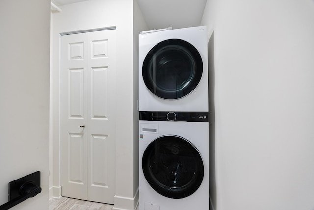 washroom with light hardwood / wood-style flooring and stacked washer / drying machine