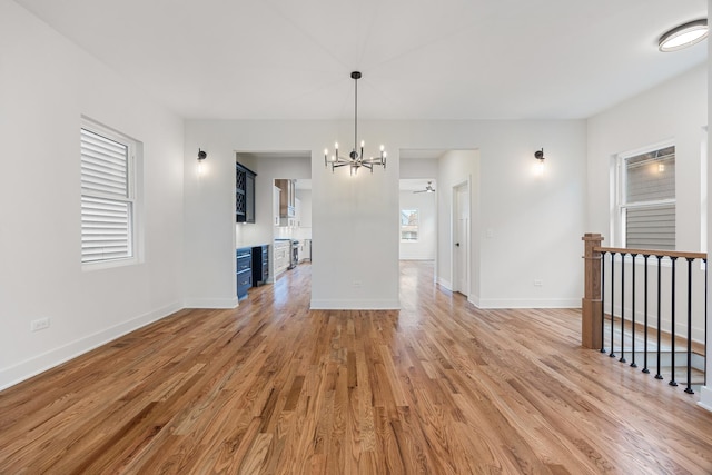 interior space featuring ceiling fan with notable chandelier and light wood-type flooring