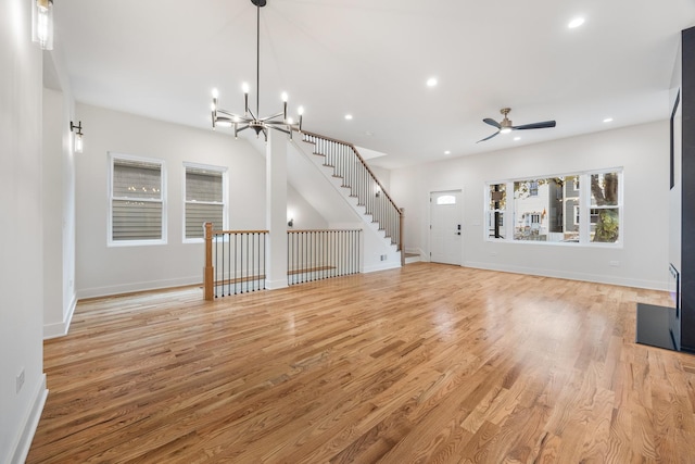 unfurnished living room with ceiling fan with notable chandelier and light wood-type flooring