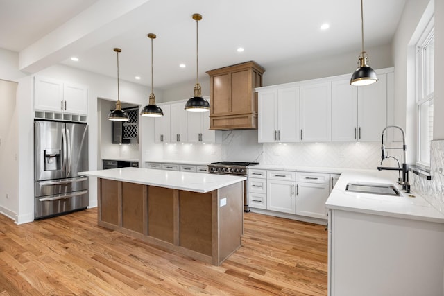 kitchen featuring white cabinetry, sink, stainless steel appliances, decorative light fixtures, and a kitchen island