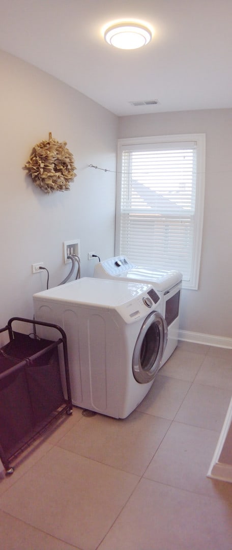 laundry room featuring separate washer and dryer and light tile patterned floors