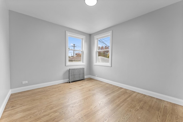 empty room with radiator heating unit and light hardwood / wood-style flooring