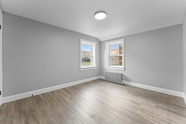 spare room featuring radiator heating unit and light hardwood / wood-style flooring