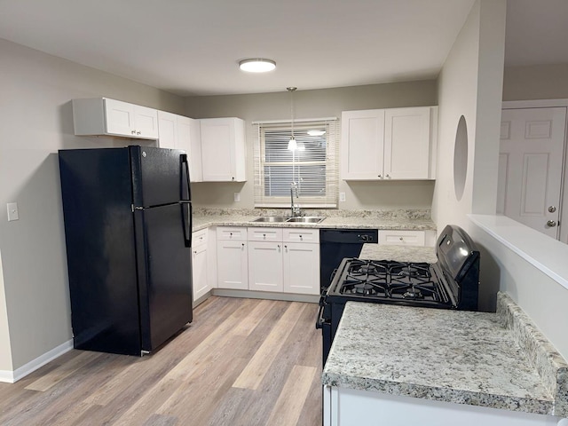 kitchen with sink, hanging light fixtures, light hardwood / wood-style floors, white cabinets, and black appliances