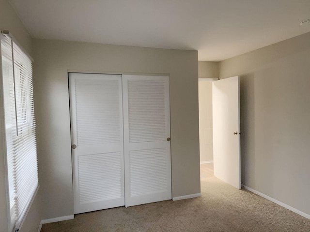 unfurnished bedroom featuring light colored carpet and a closet