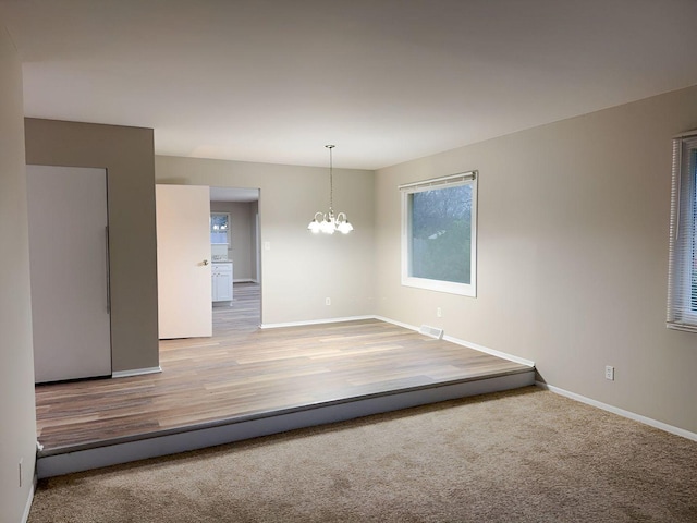 carpeted spare room featuring a notable chandelier