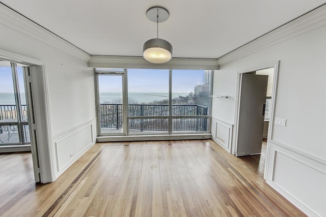 unfurnished room featuring plenty of natural light, ornamental molding, and hardwood / wood-style flooring