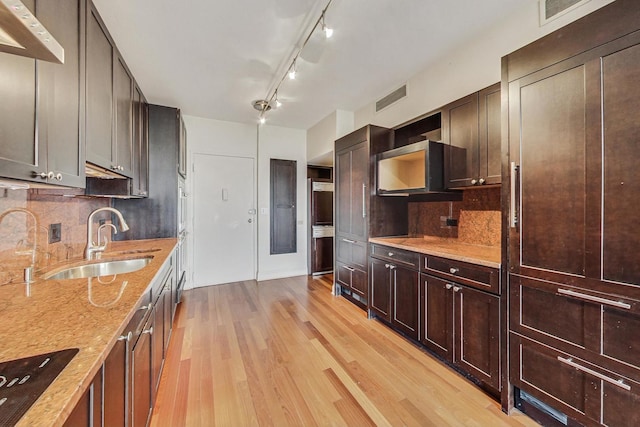 kitchen with light stone countertops, sink, tasteful backsplash, light hardwood / wood-style floors, and black stovetop