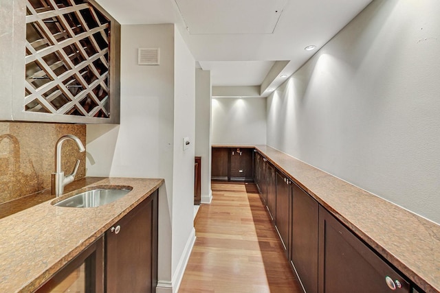 bar with backsplash, light hardwood / wood-style flooring, and sink