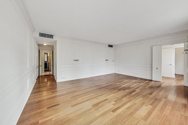 spare room featuring light wood-type flooring and crown molding