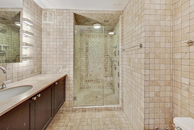 bathroom featuring vanity, toilet, tile walls, tasteful backsplash, and a shower with shower door