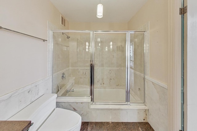 bathroom featuring toilet and shower / bath combination with glass door