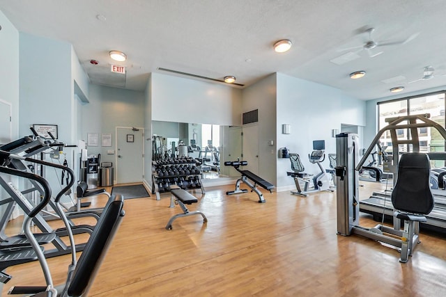 gym featuring wood-type flooring, a textured ceiling, and ceiling fan