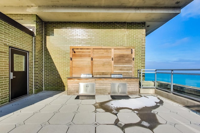 view of patio featuring a water view and exterior kitchen