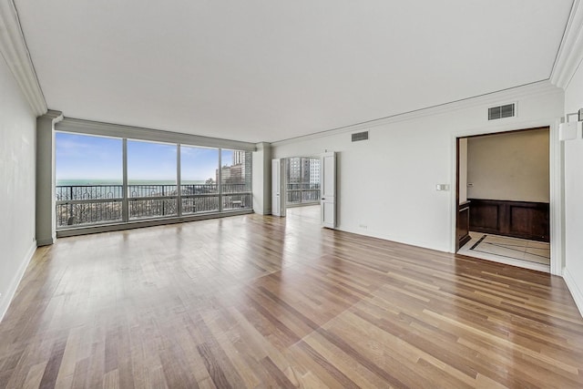 unfurnished living room with a water view, crown molding, floor to ceiling windows, and light hardwood / wood-style floors