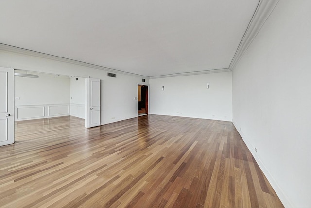 spare room with crown molding and light wood-type flooring