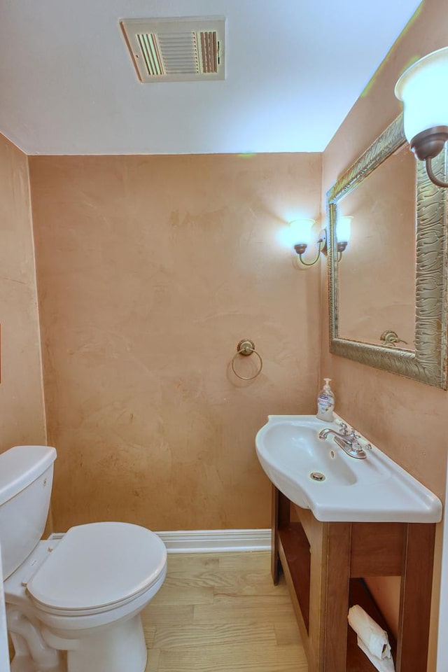 bathroom featuring vanity, hardwood / wood-style flooring, and toilet