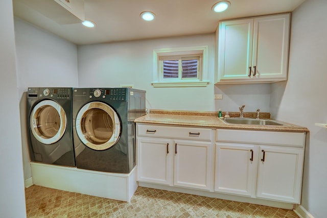 clothes washing area featuring washer and clothes dryer, cabinets, and sink