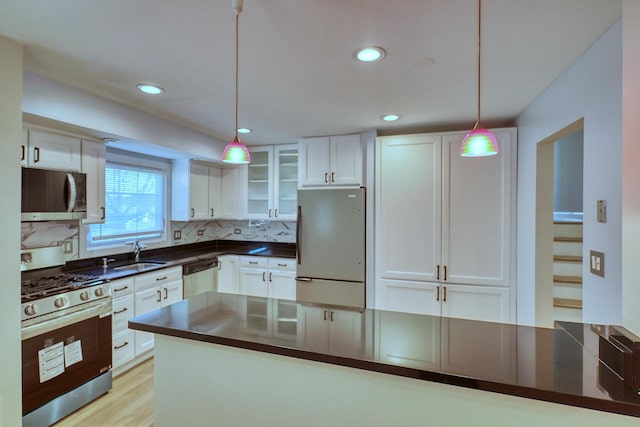 kitchen with pendant lighting, sink, decorative backsplash, white cabinetry, and stainless steel appliances