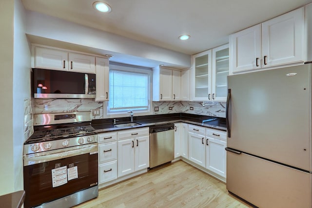 kitchen featuring white cabinetry, sink, stainless steel appliances, and light hardwood / wood-style floors