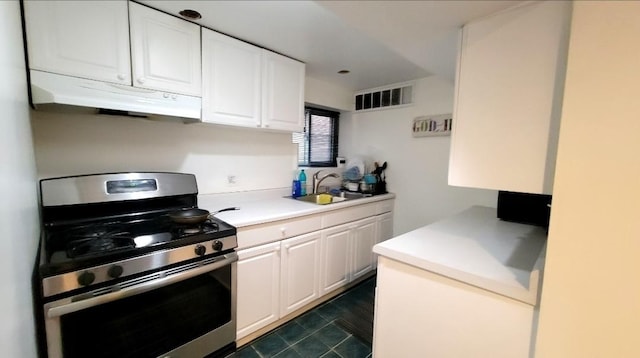 kitchen featuring stainless steel gas range oven, sink, and white cabinets