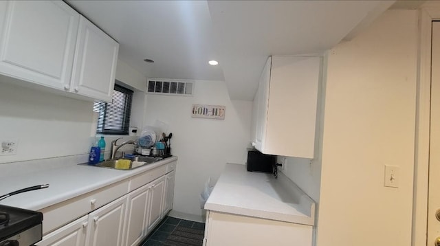 kitchen with dark tile patterned flooring, white cabinetry, black range with electric stovetop, and sink