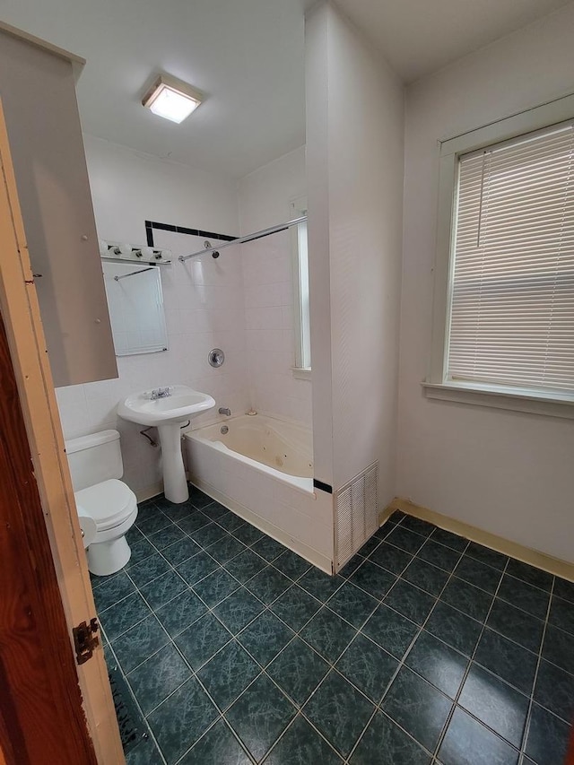 bathroom with tile patterned flooring, tiled shower / bath combo, and toilet