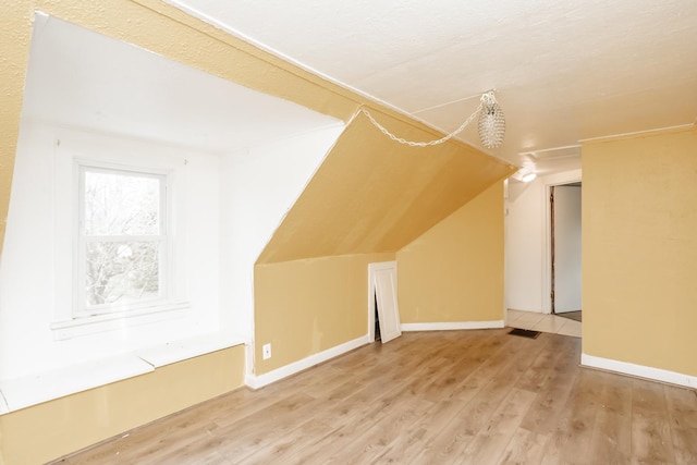 additional living space with light hardwood / wood-style floors and vaulted ceiling