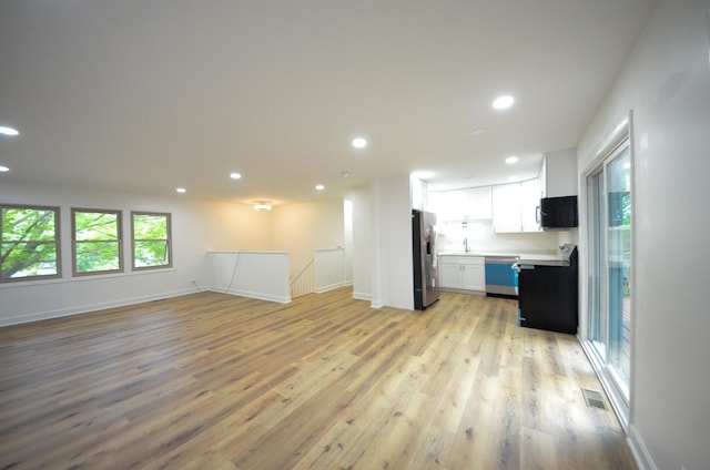 unfurnished living room featuring sink and light hardwood / wood-style floors